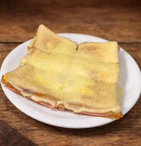 Sándwich caliente con jamón y muzzarella gratinada, cortado en cuatro